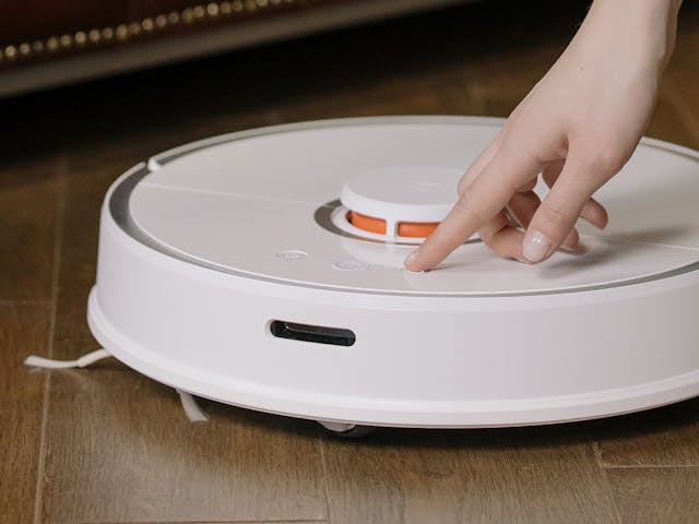 Žena uključuje robot usisivač
